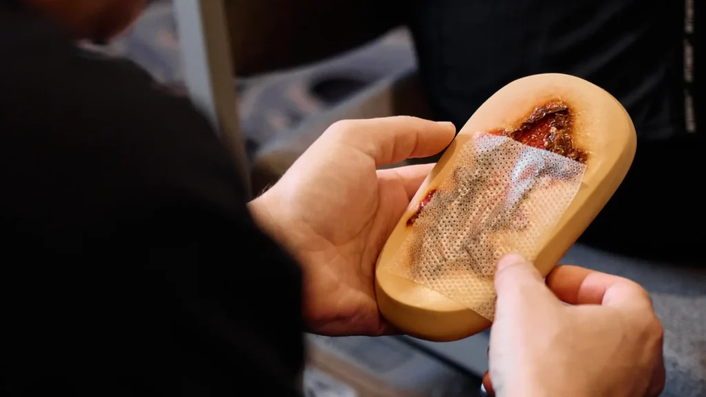 A nurse practitioner handles a model used for chronic wound care.